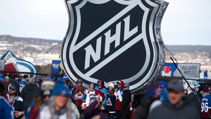 In this Feb. 15, 2020, file photo, fans pose below the NHL league logo at a display outside...