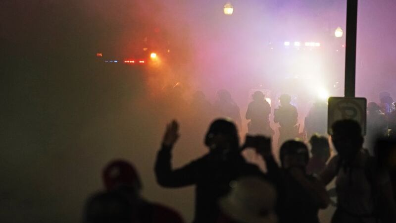 Police in riot gear clear the area in front of Kenosha County Courthouse during clashes with...