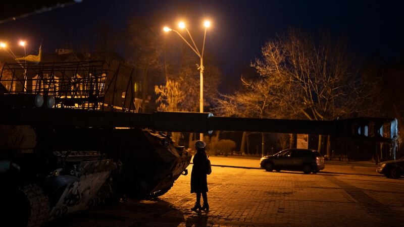 A woman stands in front of a display of destroyed Russian tanks and armored vehicles in...